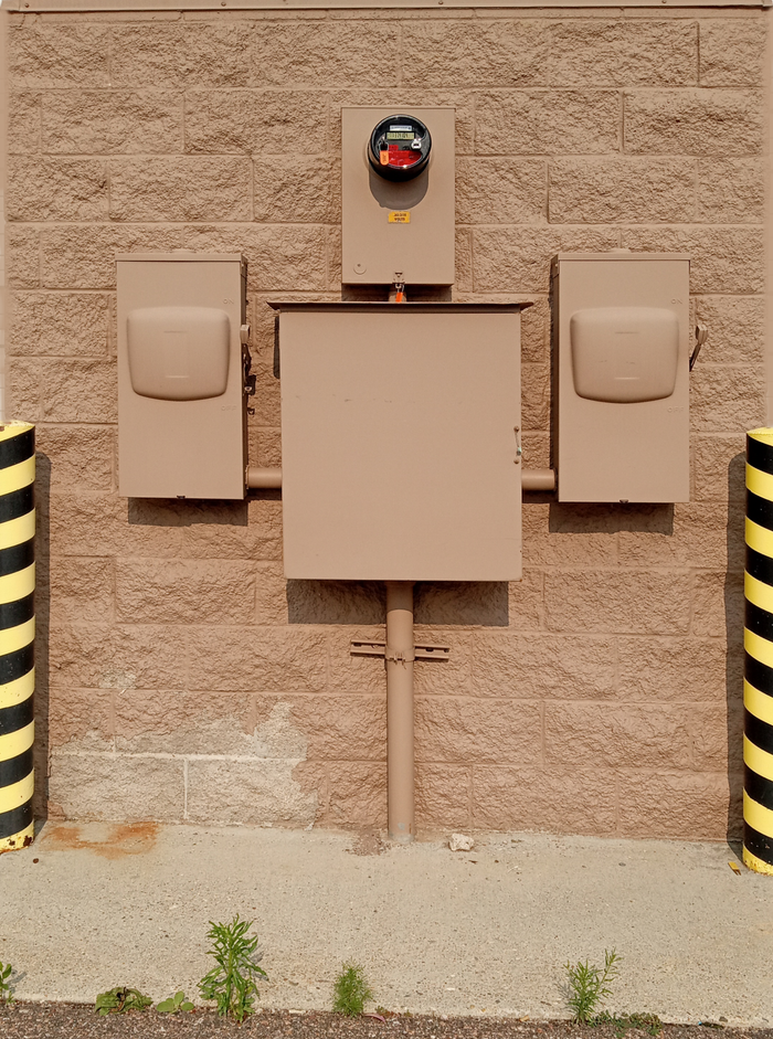 About Industrial electrical fuse box with warning stripes on an urban wall.